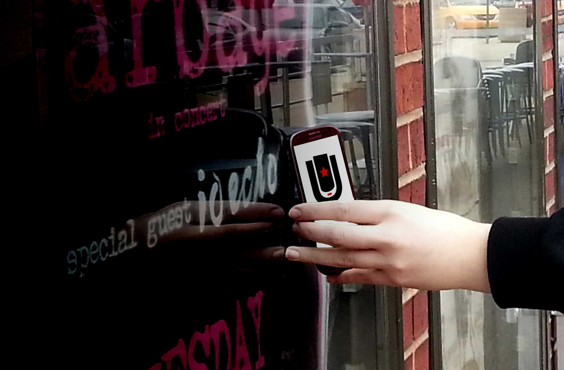 Image of hand holding a phone tapping a poster.